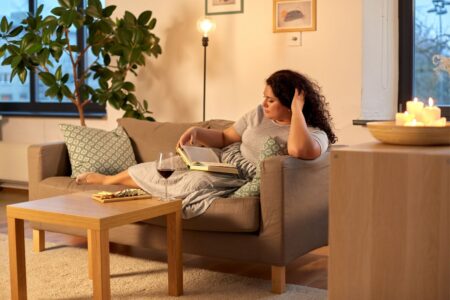 A woman relaxing on a grey sofa reading a book